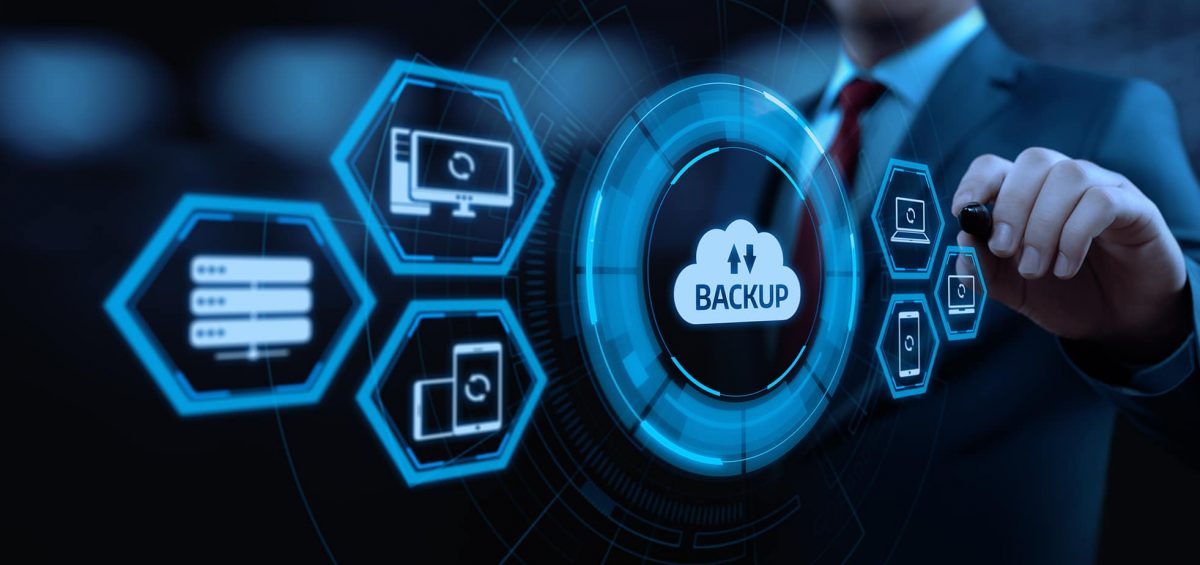  A businessman in a suit and tie draws a circle around the word 'Backup' on a virtual screen with a flowchart of cloud disaster recovery strategies.